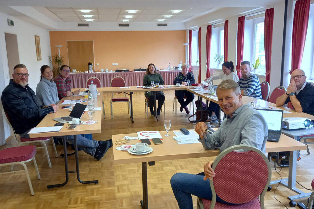 Gruppe von Menschen in einem Besprechungsraum am Tisch sitzend