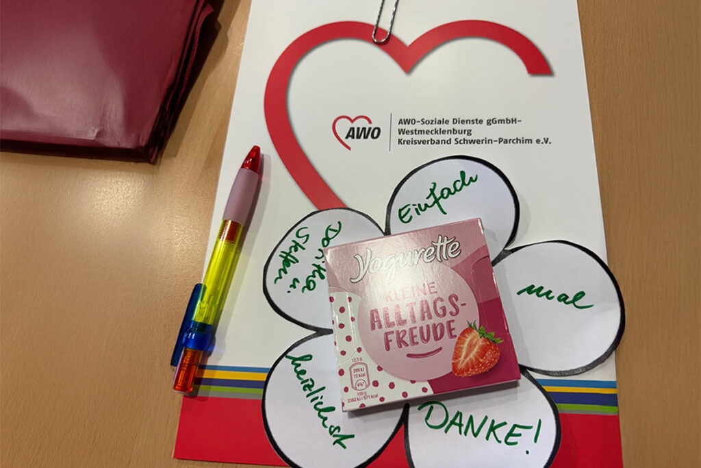 Arbeitsoberfl&auml;che mit AWO-Unterlagen, Yogurette-Schokolade und buntem Stift.