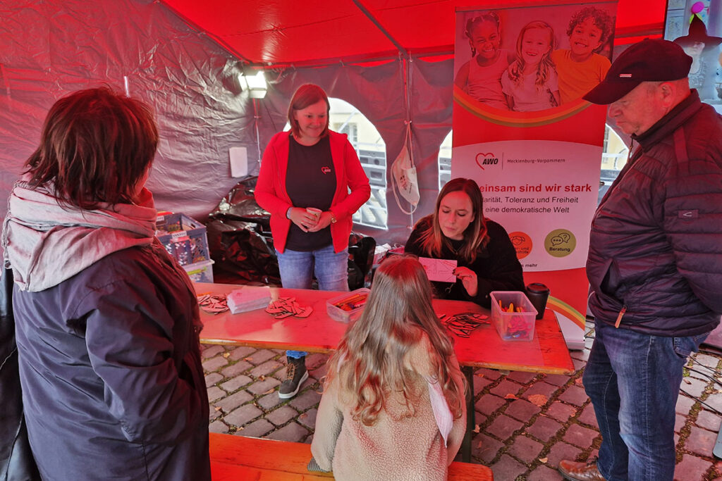 Menschen in einem rot beleuchteten Zelt bei einer AWO-Veranstaltung
