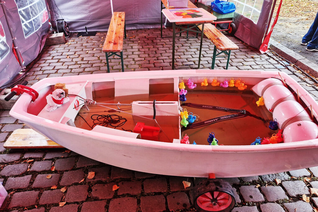 Ein kleines Boot in einem Zelt auf Kopfsteinpflaster.