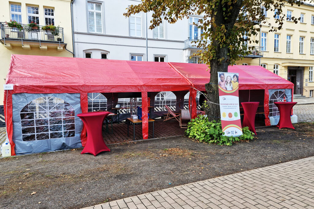 Rotes Zelt mit Tischen und Banner davor