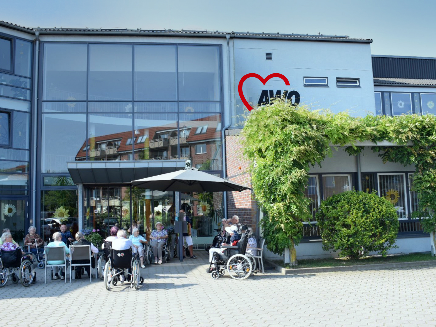Außenansicht eines AWO-Gebäudes mit Menschen auf der Terrasse