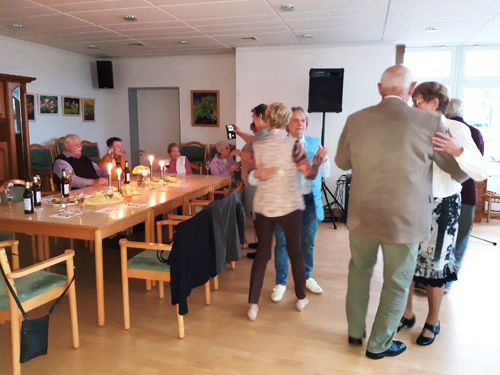 Ein Gruppenraum mit tanzenden und sitzenden Menschen