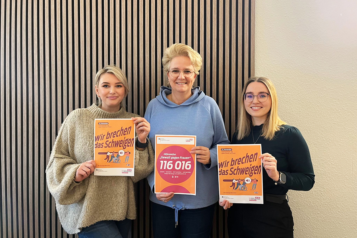 Drei Personen halten Plakate in den Händen.