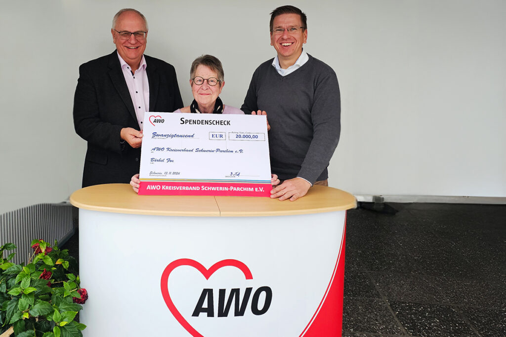 Drei Personen halten einen großen Spendenscheck der AWO