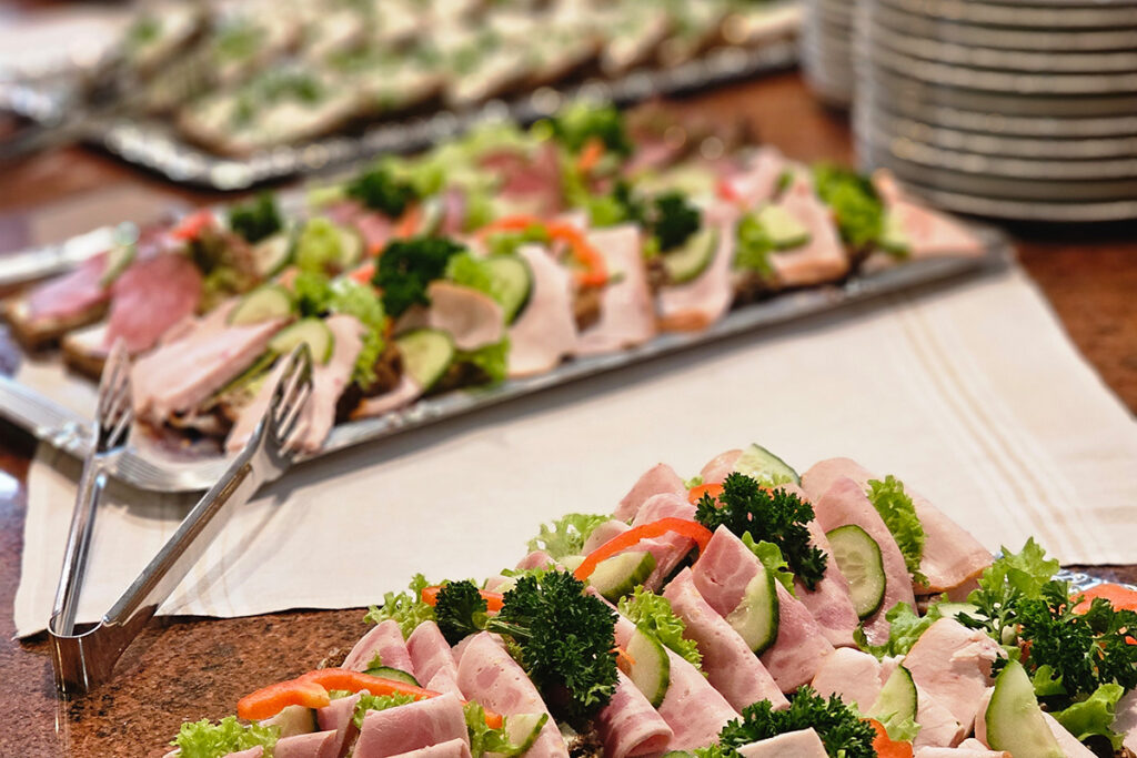 Ein Tisch mit Platten von belegten Br&ouml;tchen, dekoriert mit Gem&uuml;se und Kr&auml;utern.