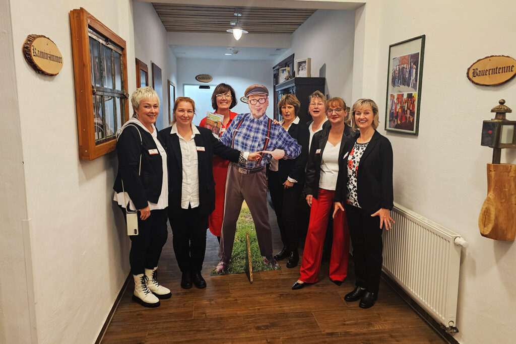 Gruppe von Frauen posiert in einem Flur neben einer Pappfigur