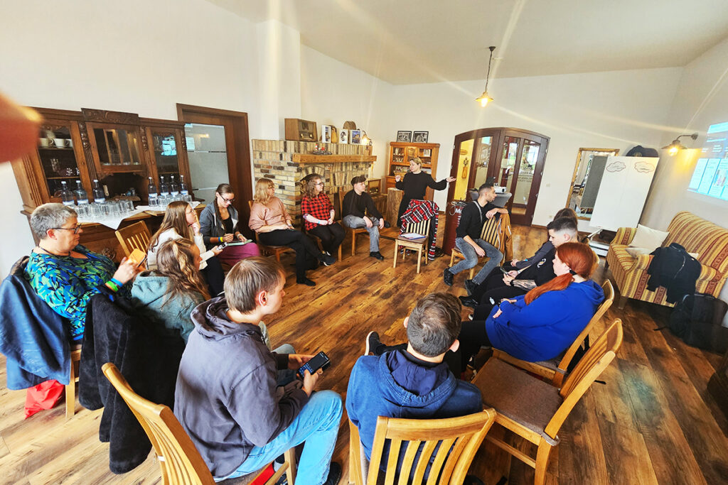 Eine Gruppe von Menschen sitzt in einem Kreis in einem Raum und hat eine Besprechung.