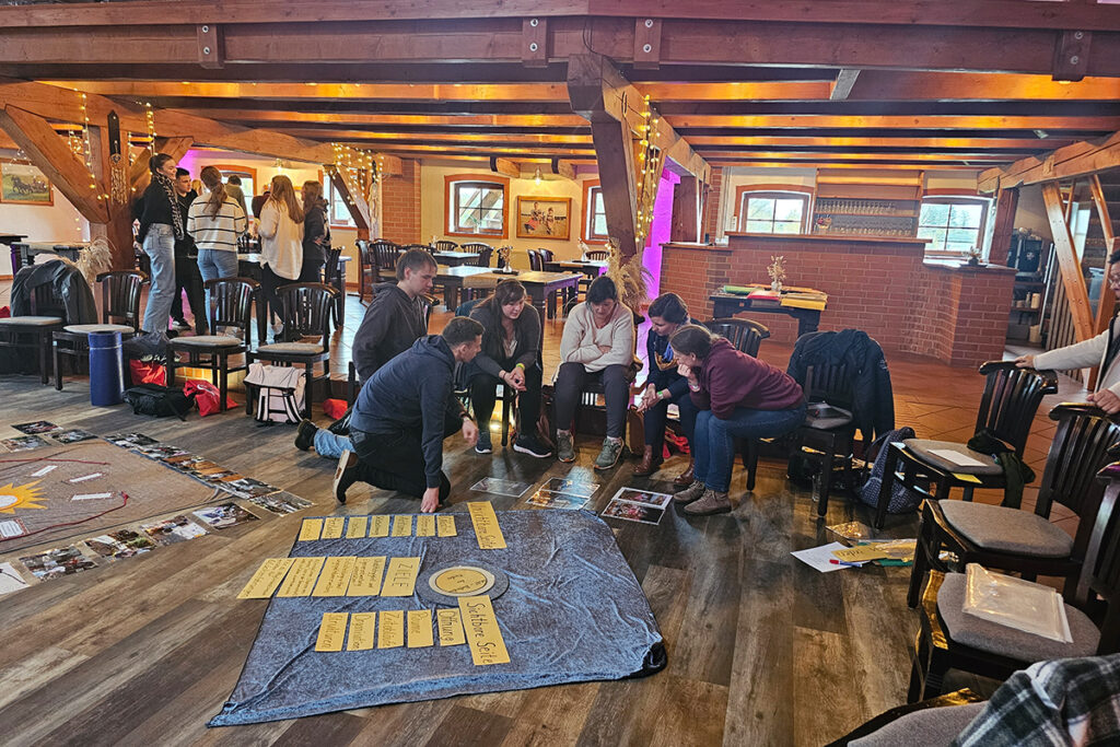 Eine Gruppe von Menschen bei einem Workshop in einem Raum mit Holzbalken.