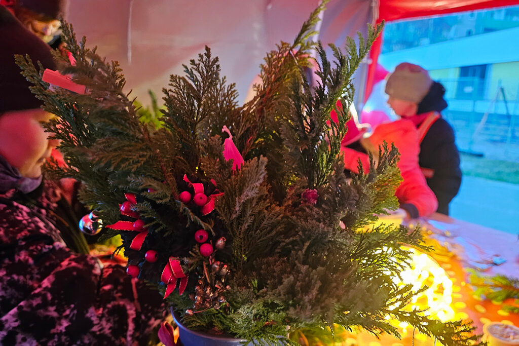 Weihnachtlich dekoriertes Gesteck mit Menschen im Hintergrund