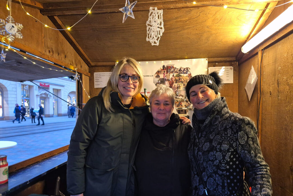 Drei Personen in einem Holzhäuschen mit Weihnachtsdekoration.