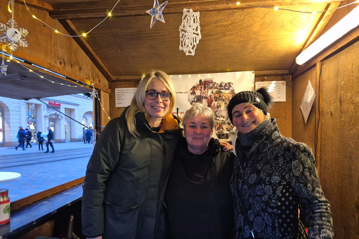 Drei Personen in einem Holzhäuschen mit Weihnachtsdekoration.