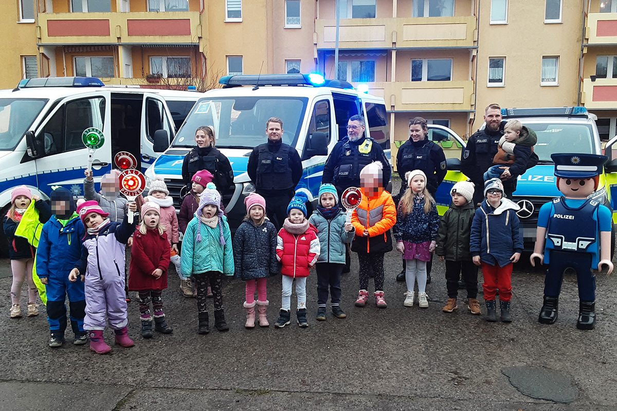 Eine Gruppe von Kindern und Polizisten vor Polizeiautos