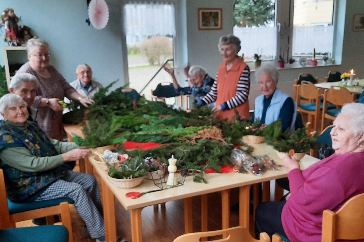 Gruppe von älteren Menschen bei der gemeinsamen Bastelarbeit an einem Tisch.