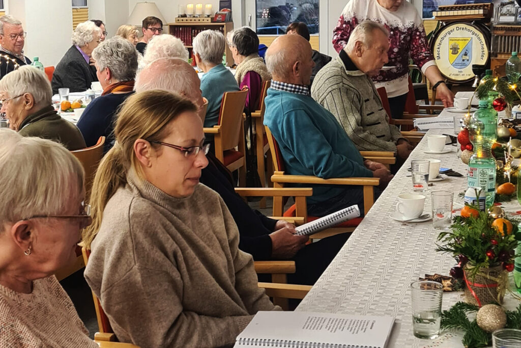 Menschen bei einer Veranstaltung, die an einem Tisch mit Dekorationen sitzen.