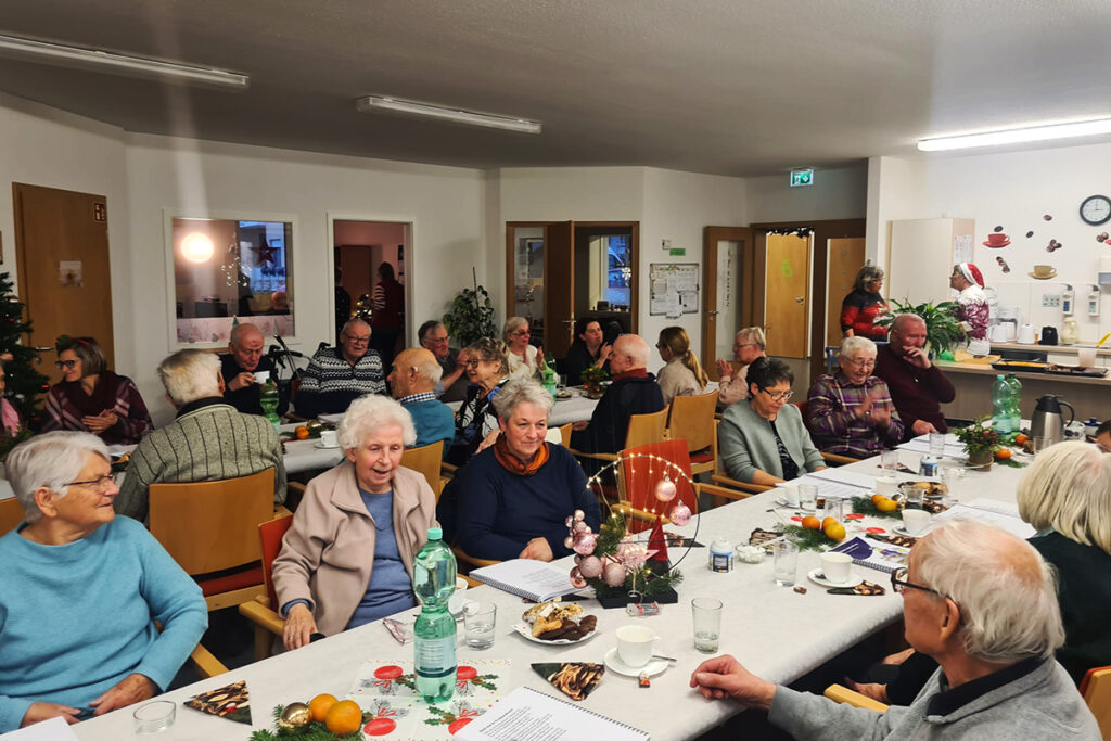 Ein Gemeinschaftstreffen in einem Raum mit Senioren an einem Tisch.