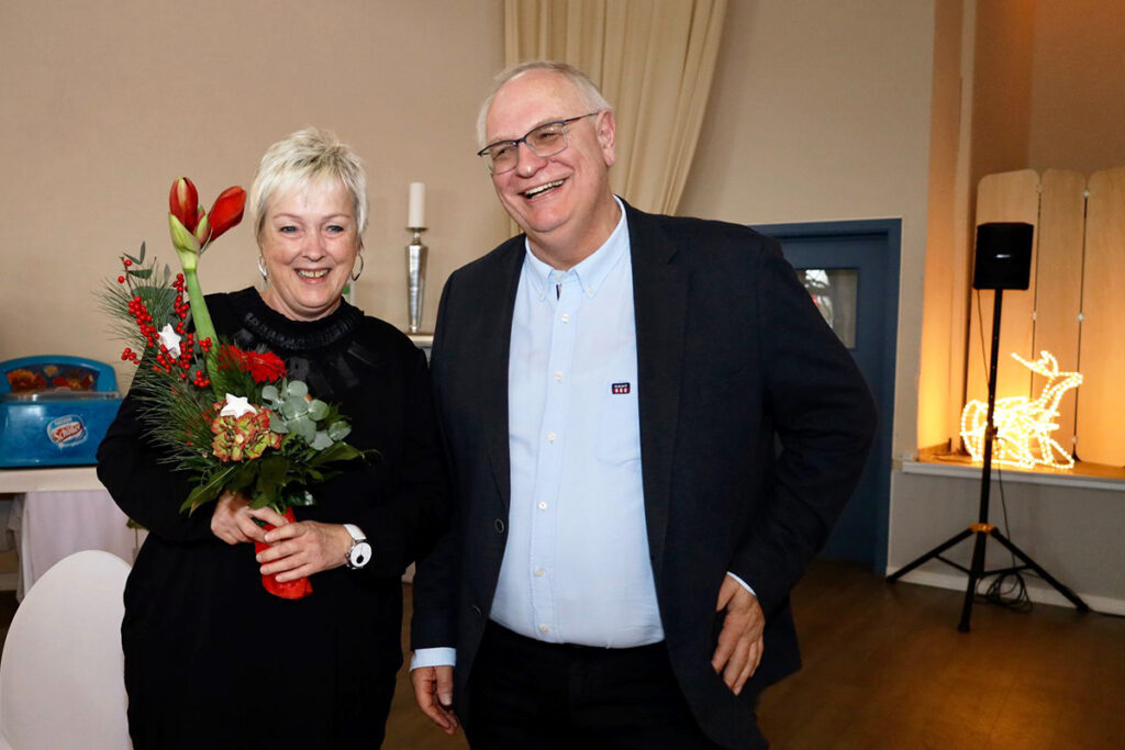 Ein Mann und eine Frau stehen nebeneinander, l&auml;chelnd. Die Frau h&auml;lt einen Blumenstrau&szlig;.