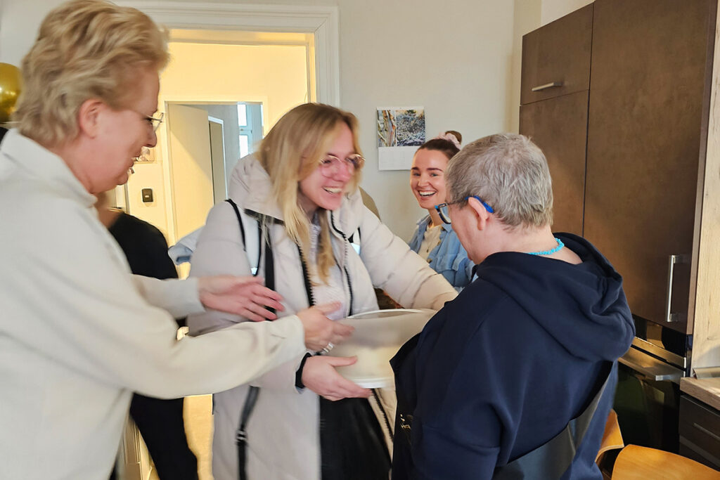 Gruppenszene mit mehreren lachenden Menschen in einer K&uuml;che