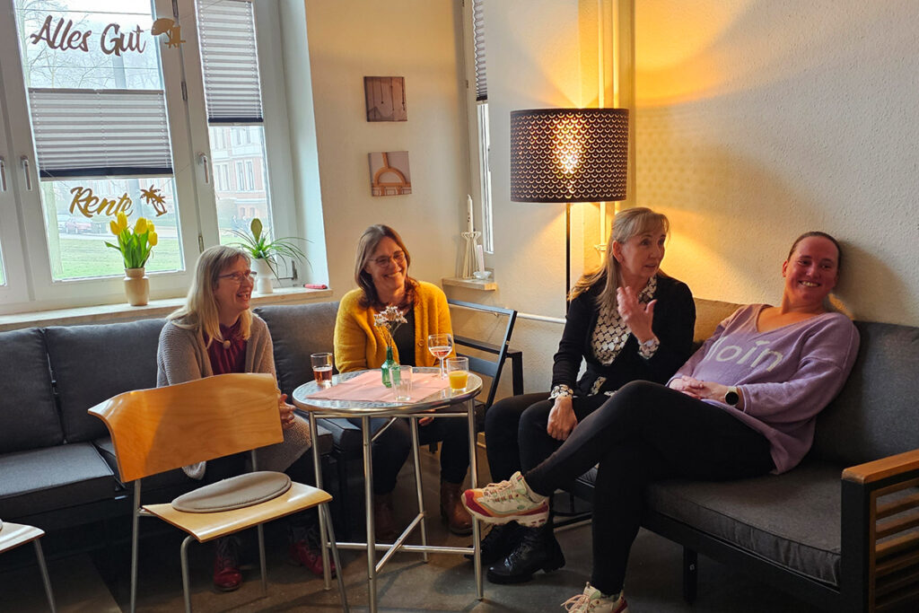 Vier Frauen sitzen und unterhalten sich in einem gem&uuml;tlichen Raum.
