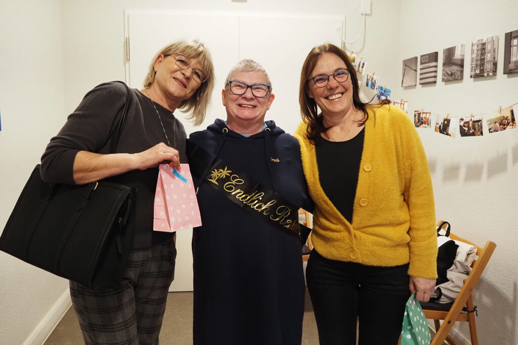 Drei Personen l&auml;cheln in die Kamera