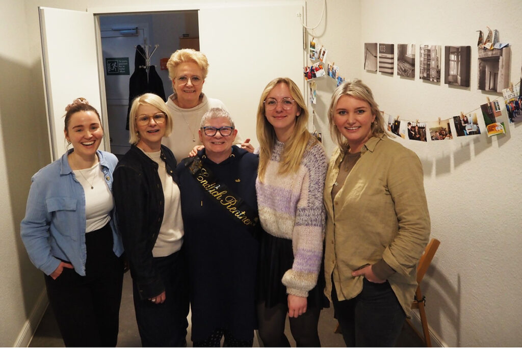 Eine Gruppe von sechs Frauen steht in einem Raum und l&auml;chelt in die Kamera.