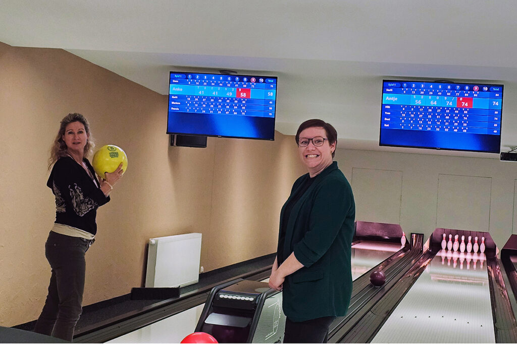 Zwei Personen beim Bowling vor Anzeigetafeln