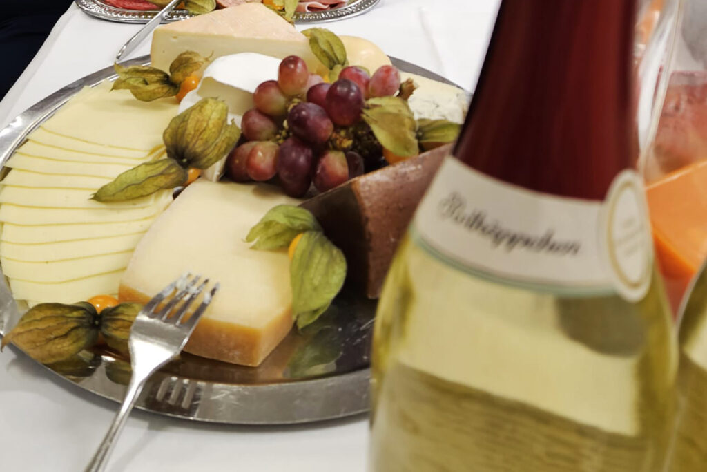 Ein Tisch mit einer K&auml;seplatte und einer Flasche Sekt