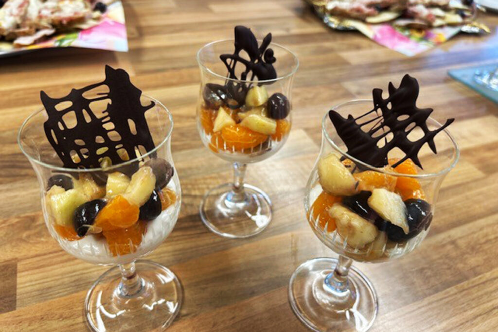 Drei mit Fr&uuml;chten gef&uuml;llte Gl&auml;ser auf einem Holztisch.