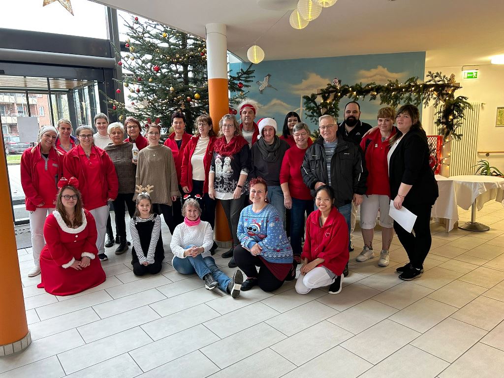 Gruppenfoto von Menschen in rot-weißer Kleidung in einem festlich geschmückten Raum.