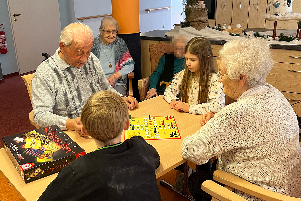 Ältere Menschen und Kinder spielen Brettspiel an einem Tisch