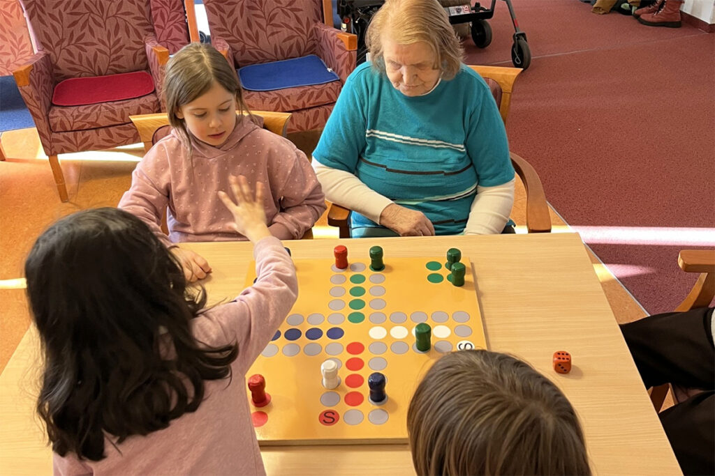 Vier Personen um einen Tisch versammelt, spielen ein Brettspiel.