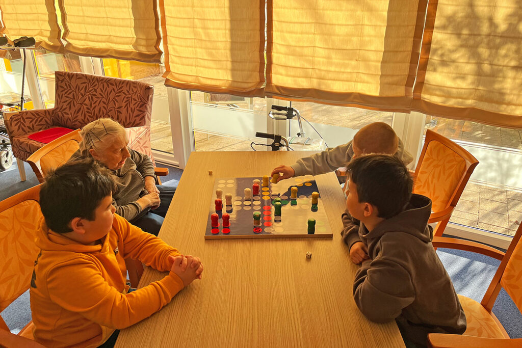 Gruppe am Tisch spielt Brettspiel in einem sonnigen Raum