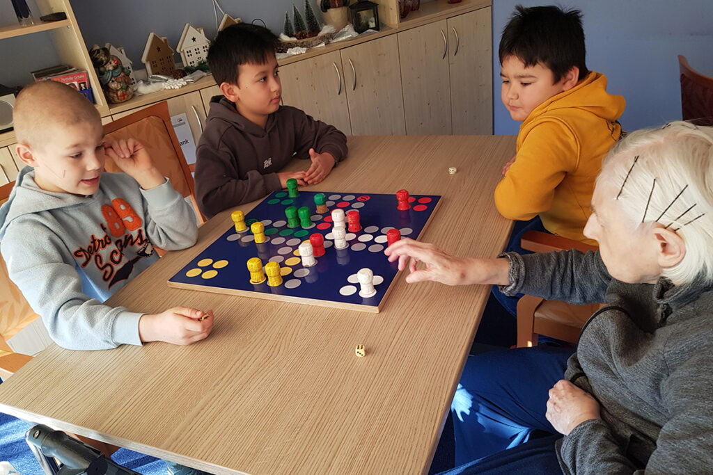 Eine Seniorin und drei Kinder spielen ein Brettspiel