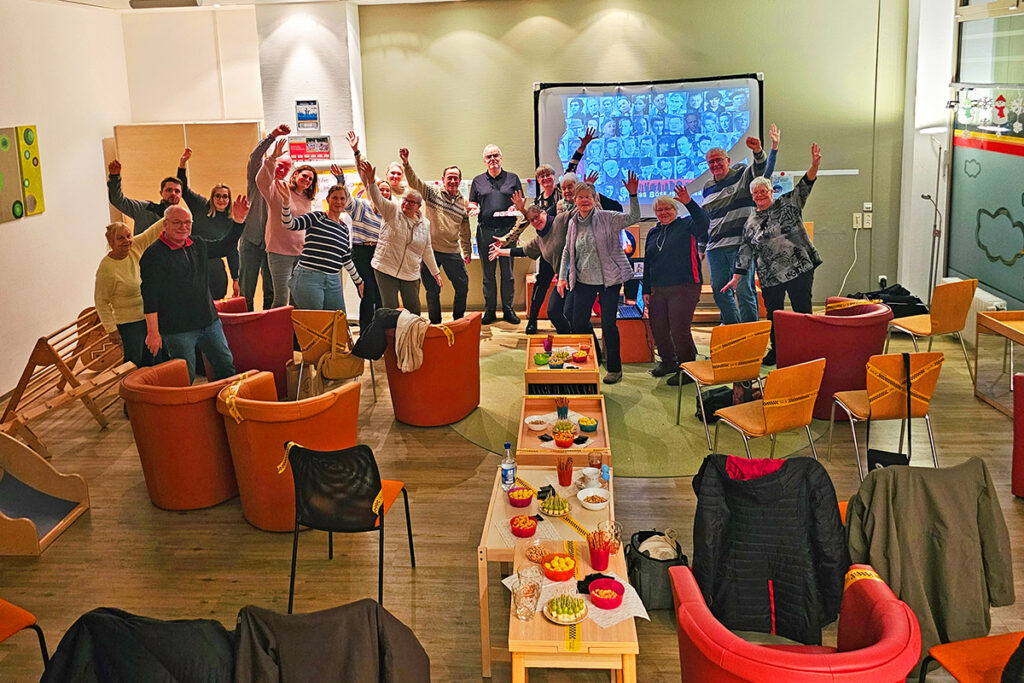 Gruppe von Menschen in einem Raum, die fröhlich posieren.