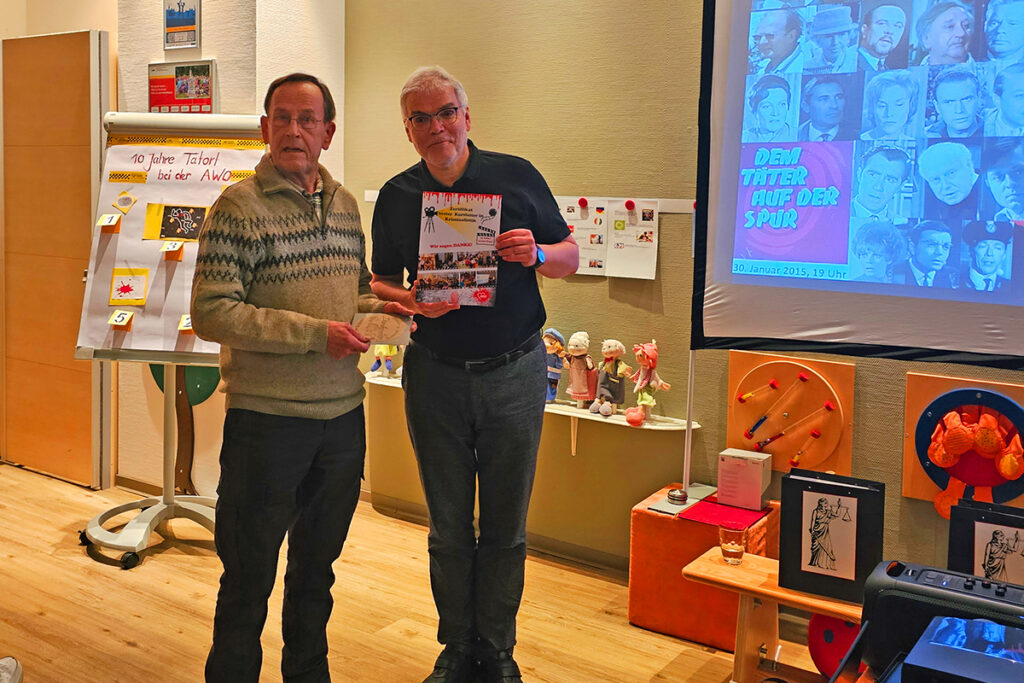 Zwei M&auml;nner stehen in einem Raum vor einer Pr&auml;sentationsfl&auml;che.