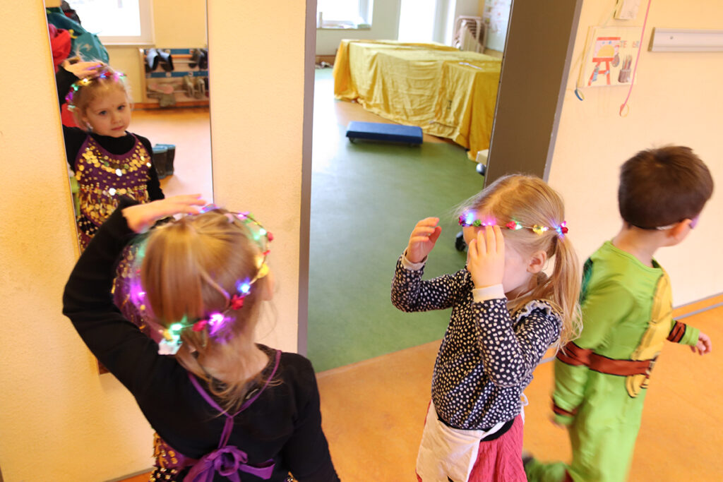 Drei Kinder verkleiden sich mit bunten Lichtern im Haar