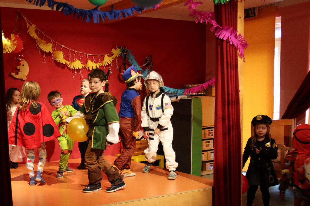 Kinder auf einer B&uuml;hne, verkleidet in verschiedenen Kost&uuml;men bei einem Karnevalsfest.