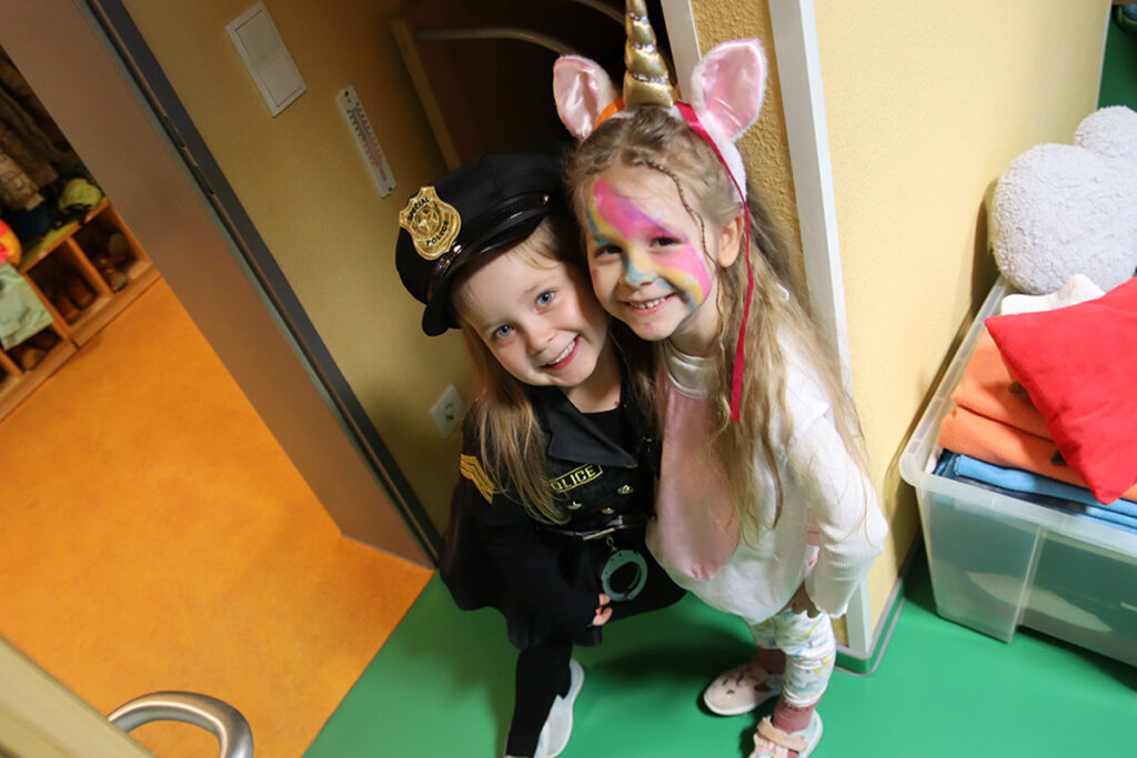 Zwei Kinder in Kost&uuml;men, l&auml;chelnd in einem Flur