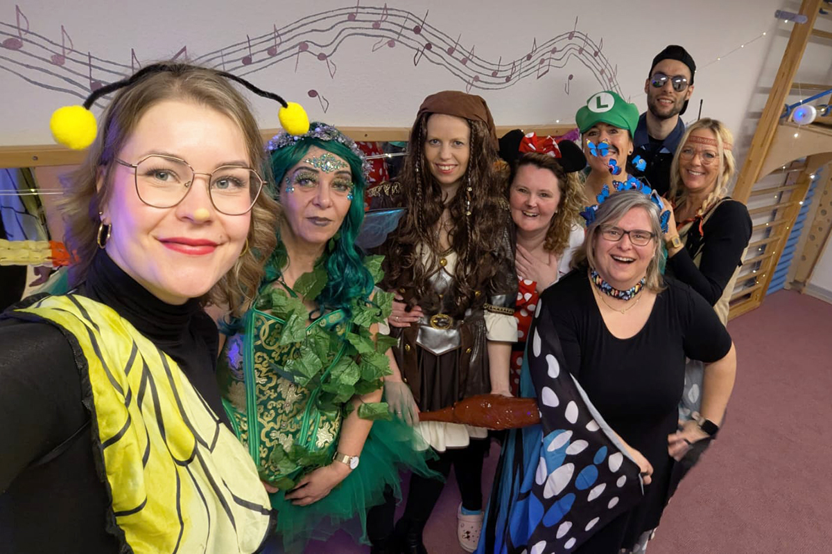 Menschen in farbenfrohen Kostümen lächeln in die Kamera.