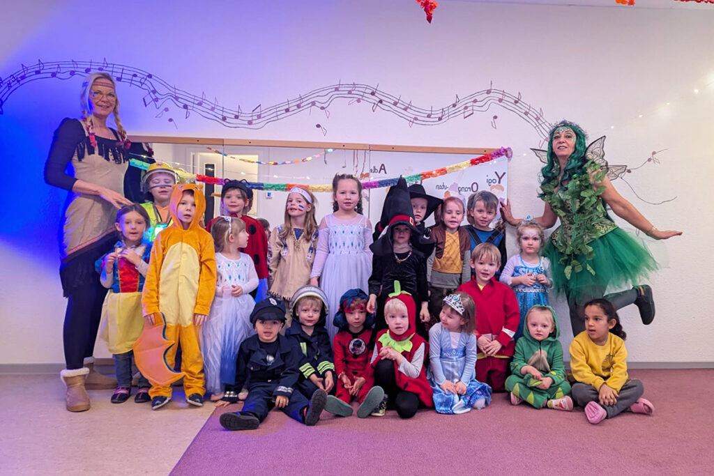 Kinder in bunten Kost&uuml;men in einem Raum mit musikalischem Dekor