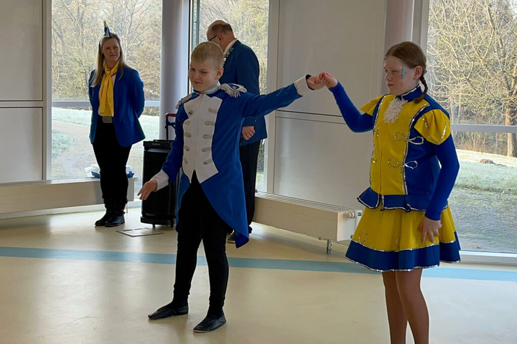 Zwei Kinder in bunten Kost&uuml;men tanzen in einem Raum.