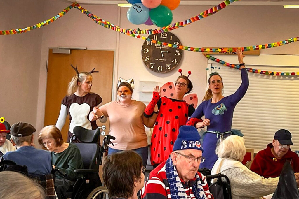 Menschen in einem Raum, einige in Tierkostümen, feiern gemeinsam