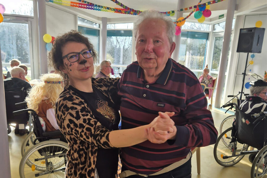 Ein Mann und eine Frau tanzen in einem festlich dekorierten Raum.