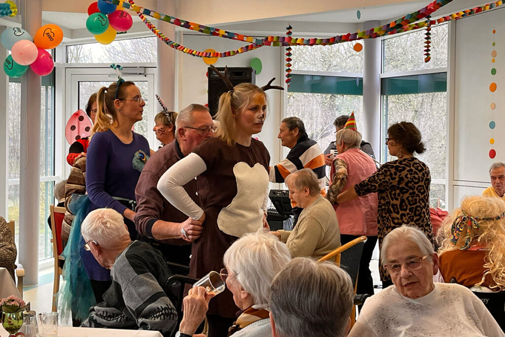 Menschen bei einer fr&ouml;hlichen Feier in einem geschm&uuml;ckten Raum.