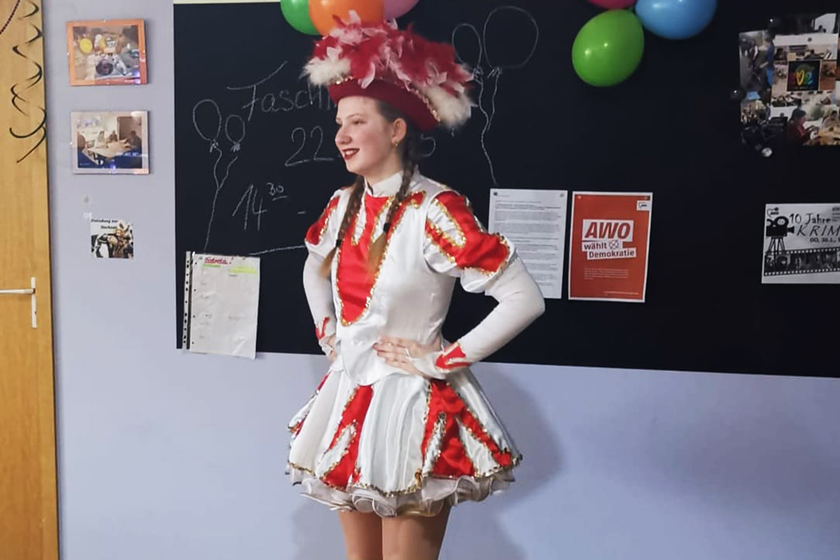 Frau in Karnevalskostüm neben einer Tafel