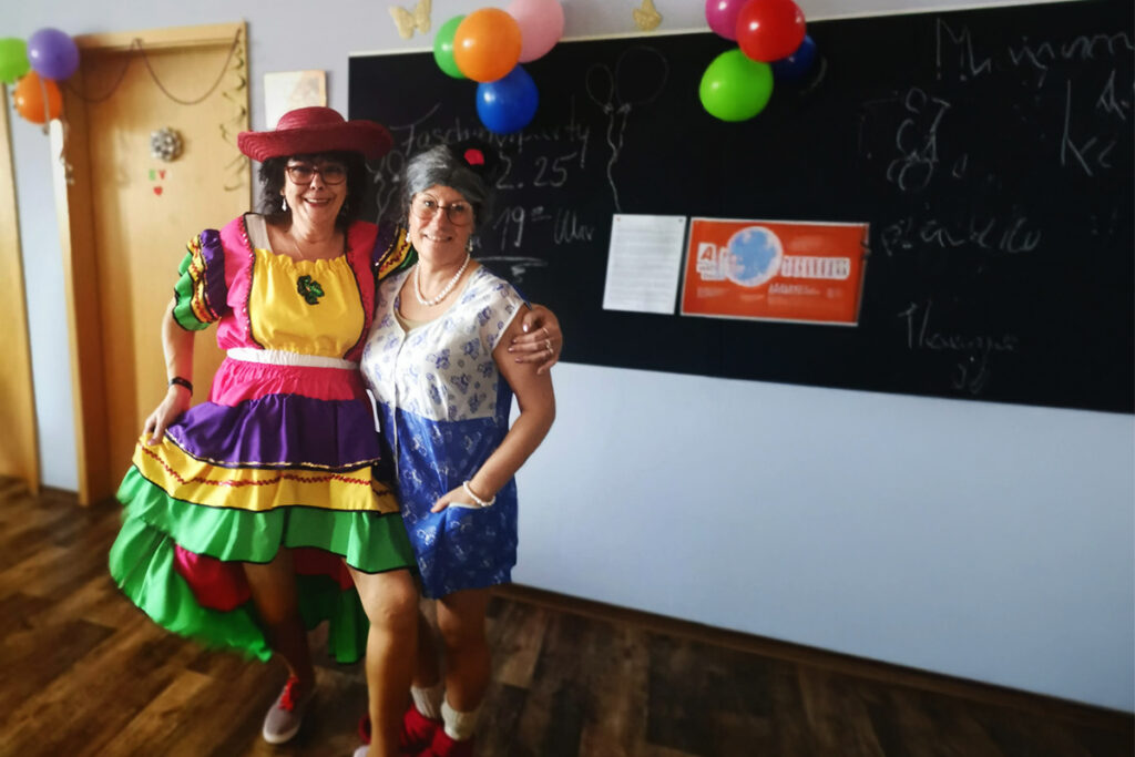 Zwei Personen in Kost&uuml;men vor einer Tafel mit Luftballons dekoriert