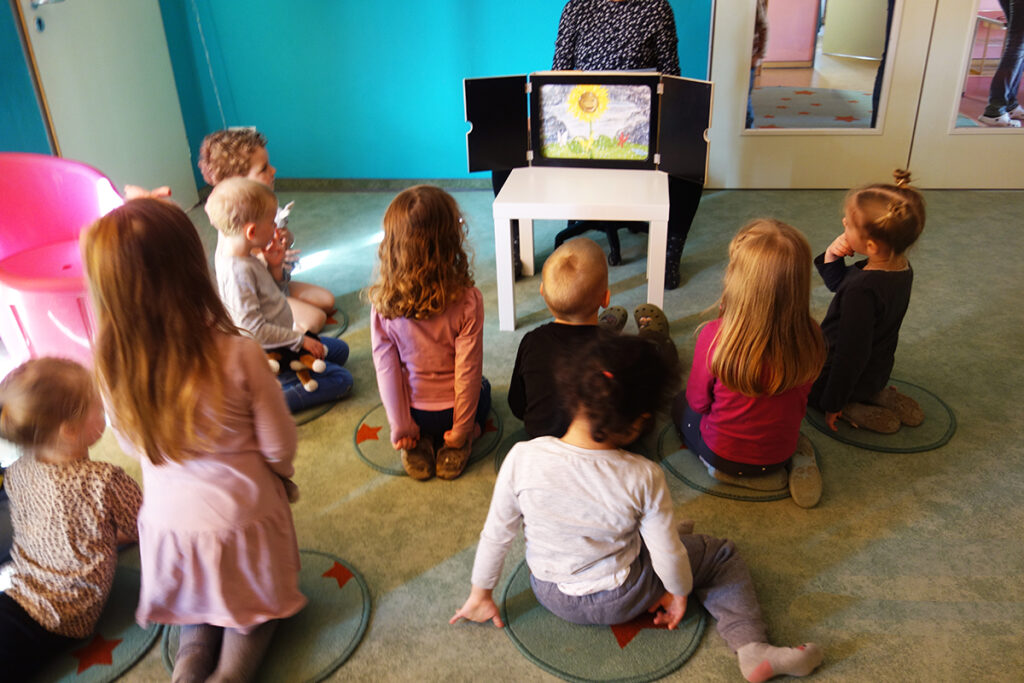 Kinder in einer Kita, die einer Geschichte lauschen.