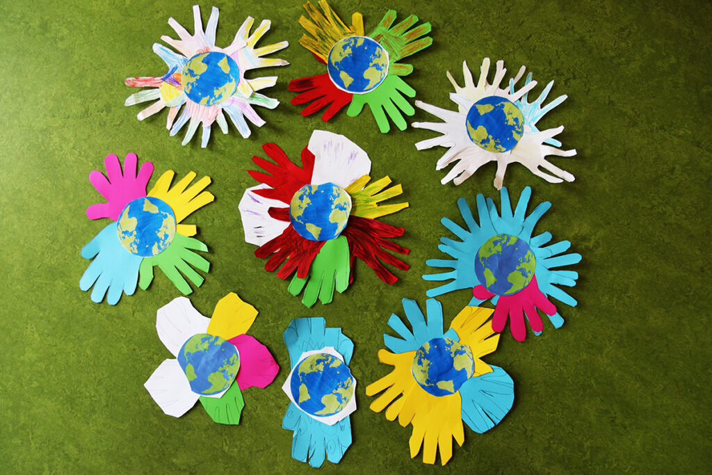 Bastelarbeit aus ausgeschnittenen bunten Papierh&auml;nden mit Erdkugel in der Mitte