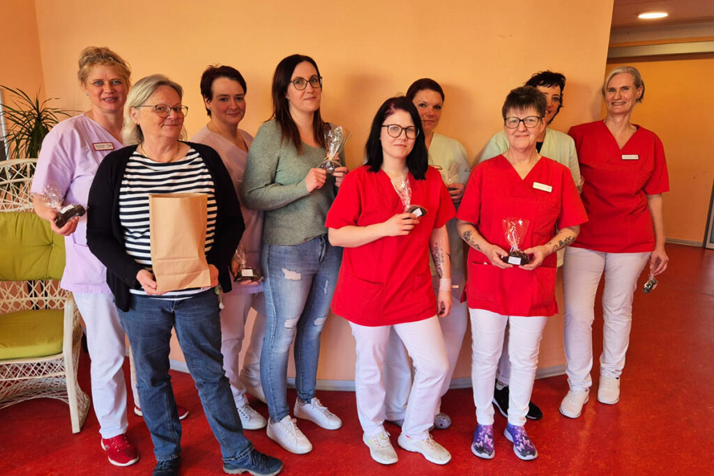 Eine Gruppe von Frauen in Arbeitskleidung h&auml;lt kleine Geschenke.