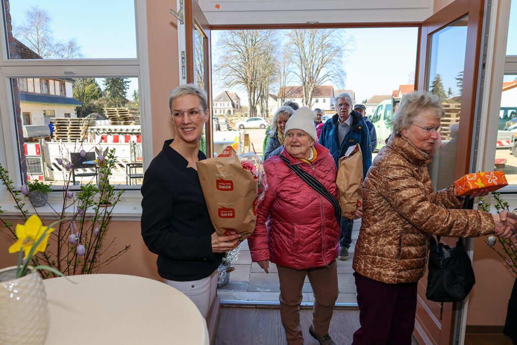 Mehrere Menschen betreten ein Geb&auml;ude und tragen Taschen.